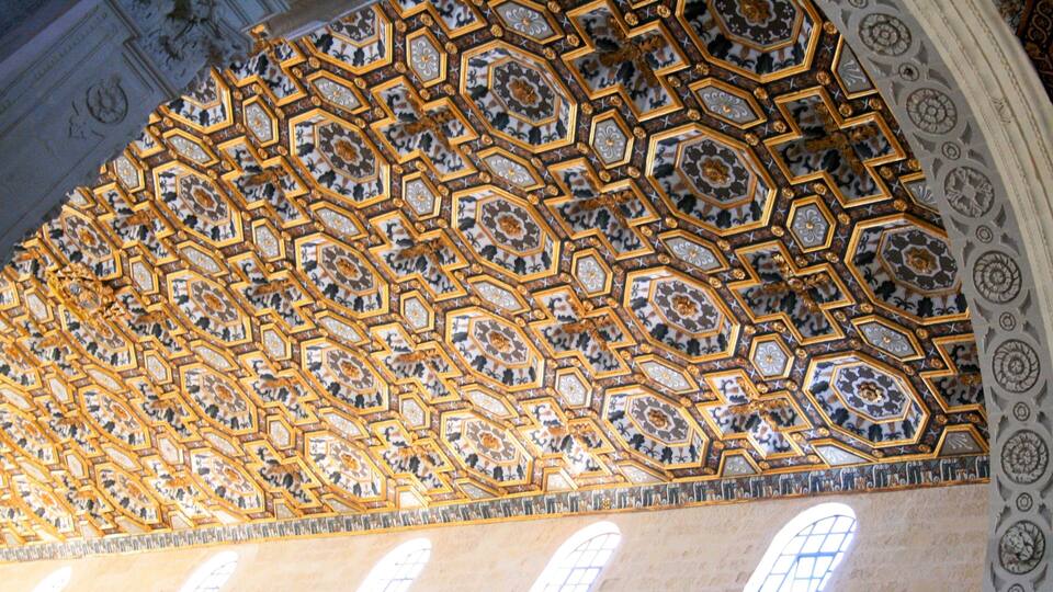 A ceiling with intricate geometric patterns and gold accents.