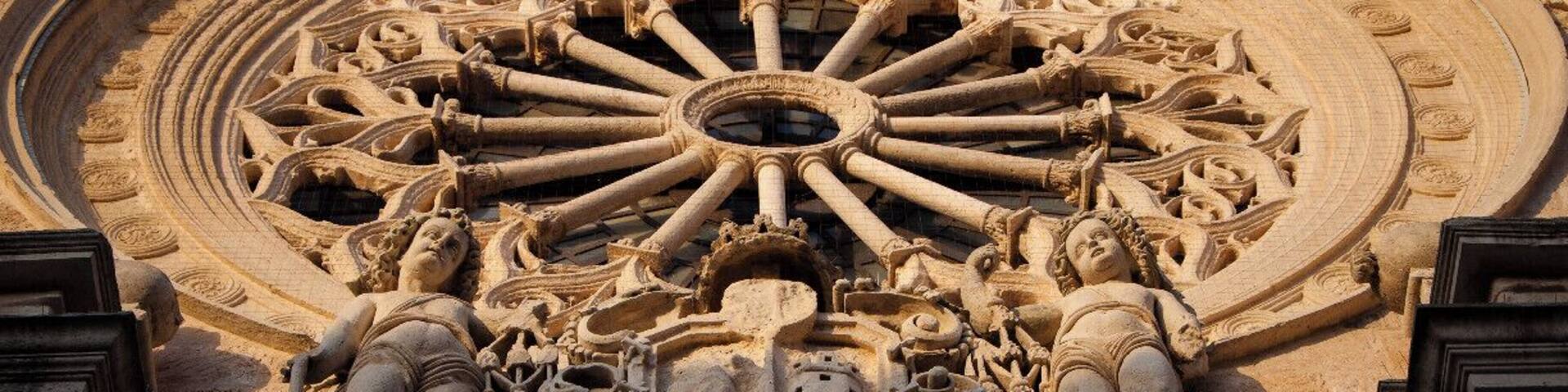 A detailed stone facade with a large circular window and intricate carvings.