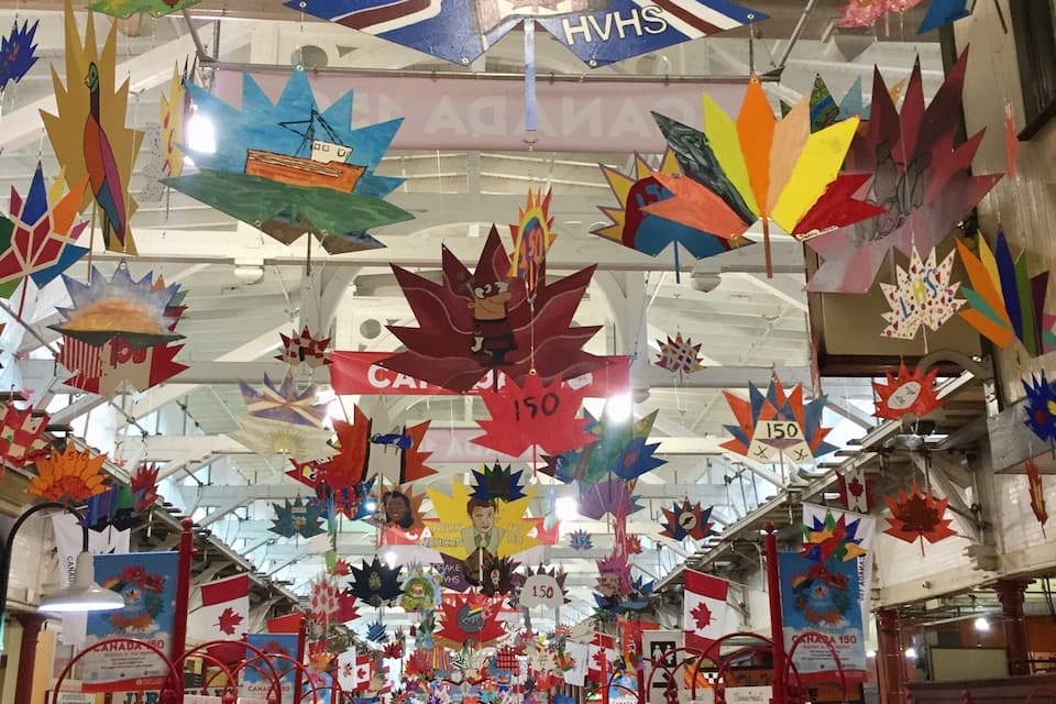 A market with colorful decorations and signs, including a prominent 'JAMES' sign and various price tags.