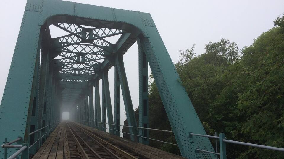 A green steel bridge with multiple tracks and a metal railing.