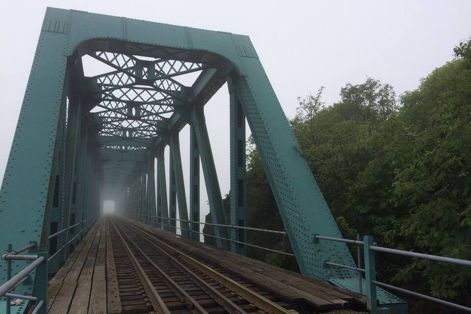 Eine grüne Stahlbrücke mit mehreren Gleisen und einem Metallgeländer.