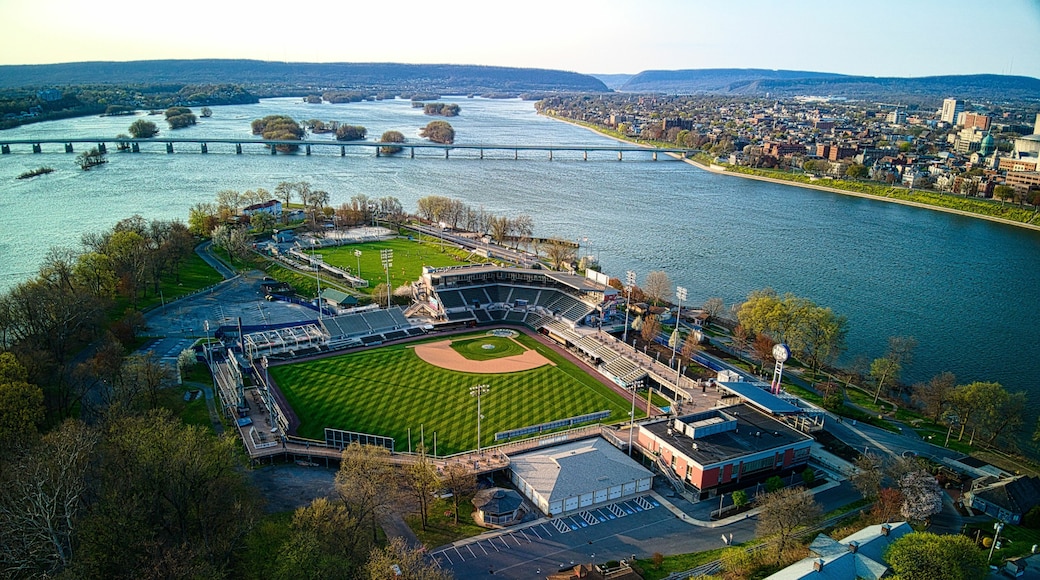 An aerial view of a baseball stadium with a river and bridge in the background.