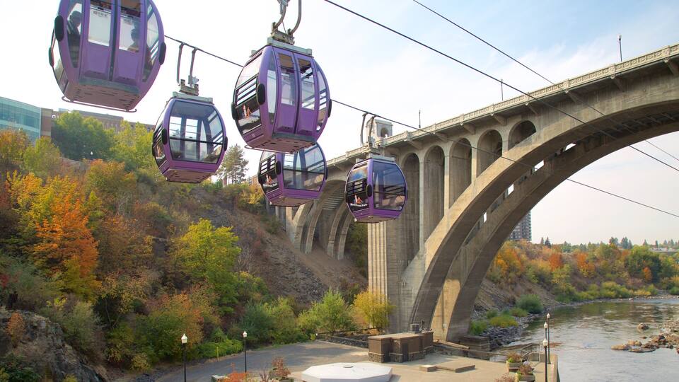 A cable car system over a bridge with autumn foliage and a river below.