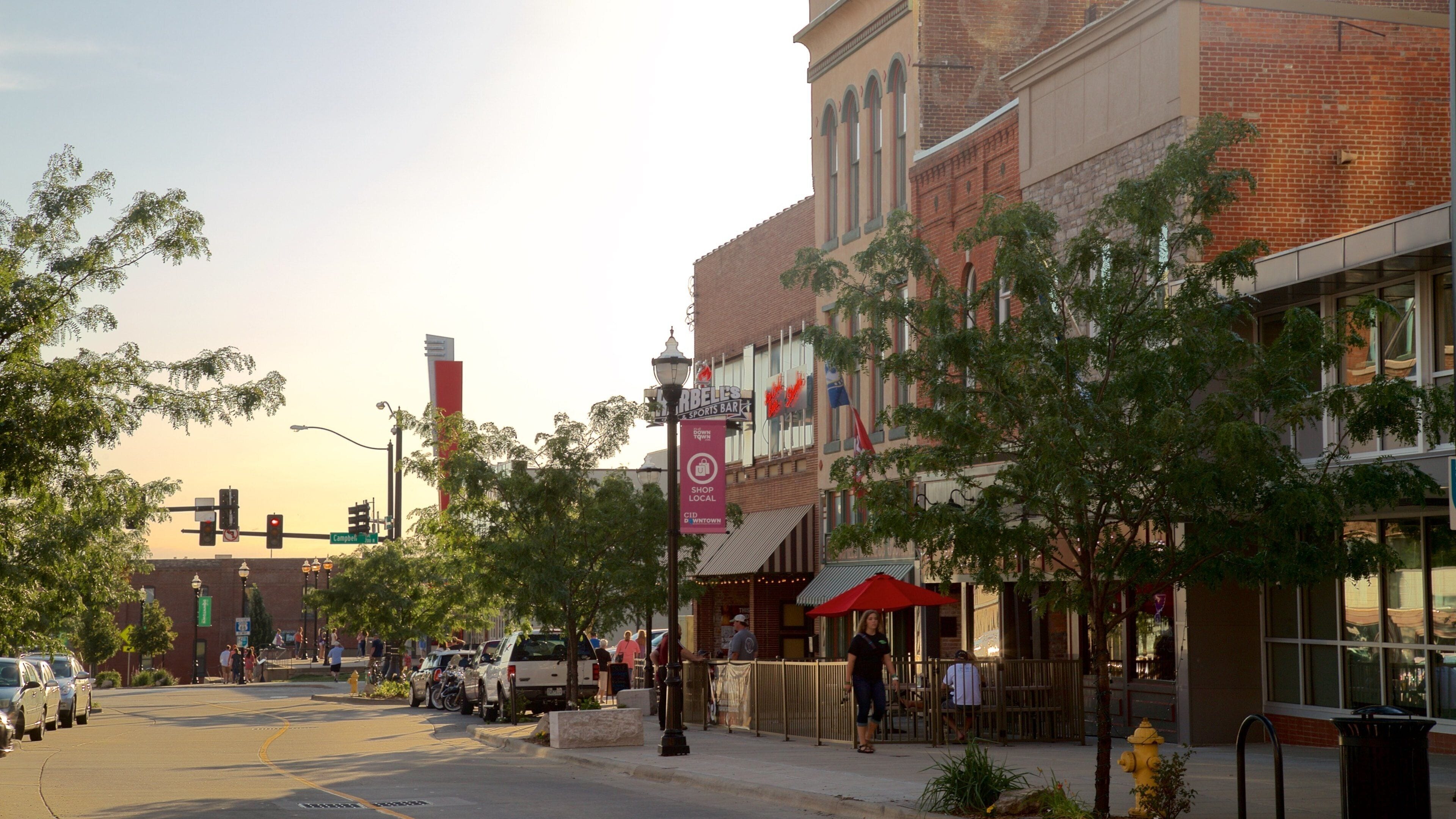 A street with a bar, trees, and a brick building.