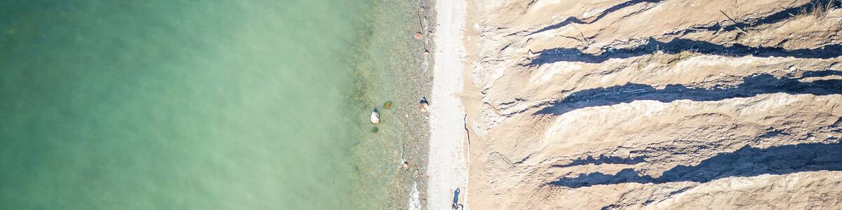 Vue aérienne d’une plage aux eaux cristallines et aux formations rocheuses en strates.