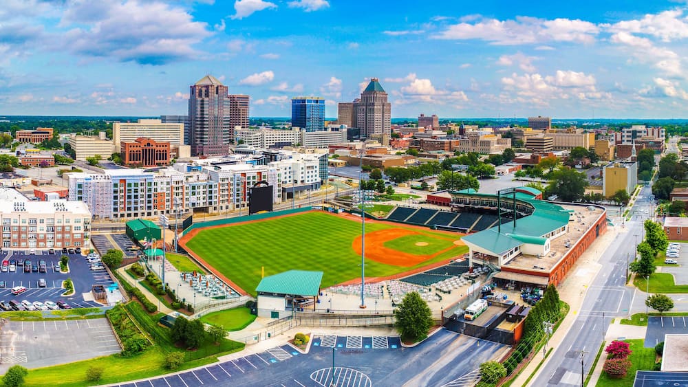 Une vue urbaine avec un stade de baseball entouré d’immeubles et d’un parking.