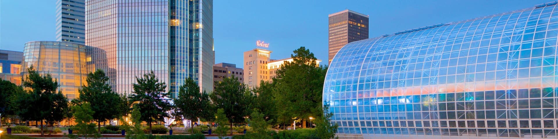 A modern cityscape with a distinctive glass building and a river.