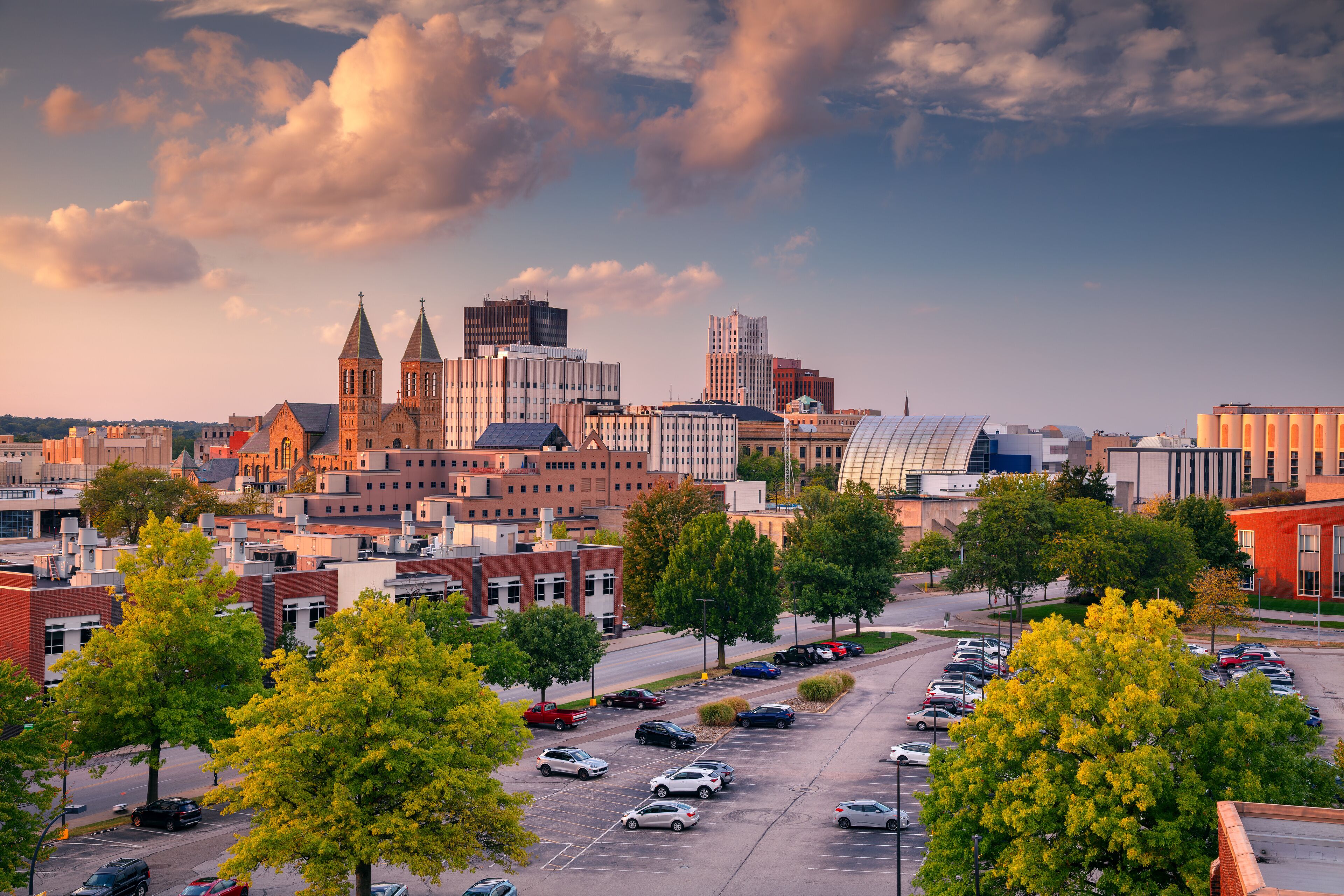 A cityscape with a prominent church, modern buildings, and a parking lot.