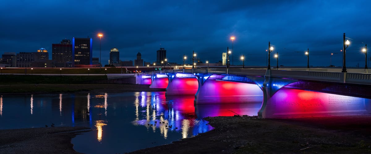 A bridge with colorful lights reflecting on the water.
