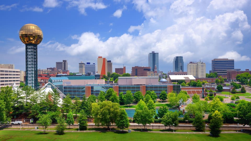 A cityscape with a prominent tower, modern buildings, and a park with trees.