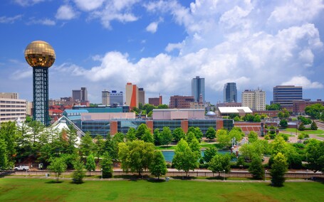 A cityscape with a prominent tower, modern buildings, and a park with trees.