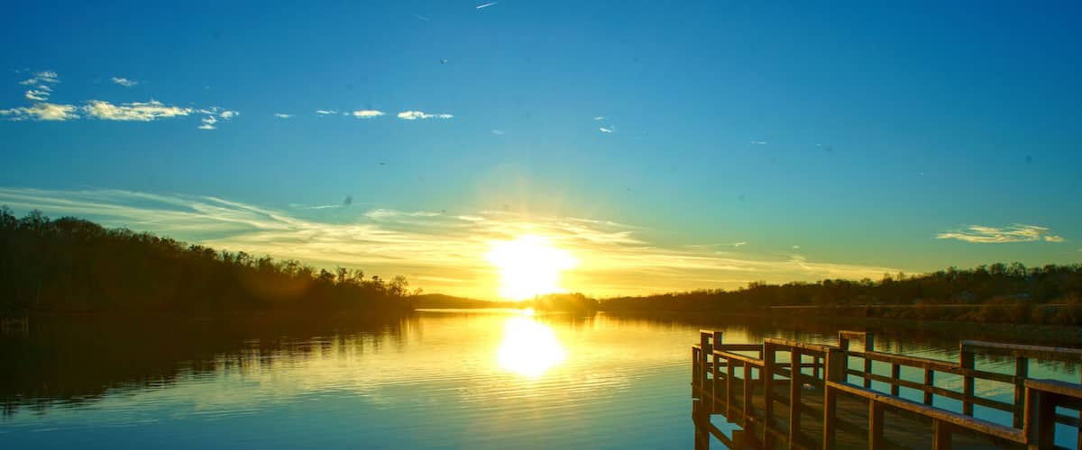 A wooden pier extending into calm water during sunset.