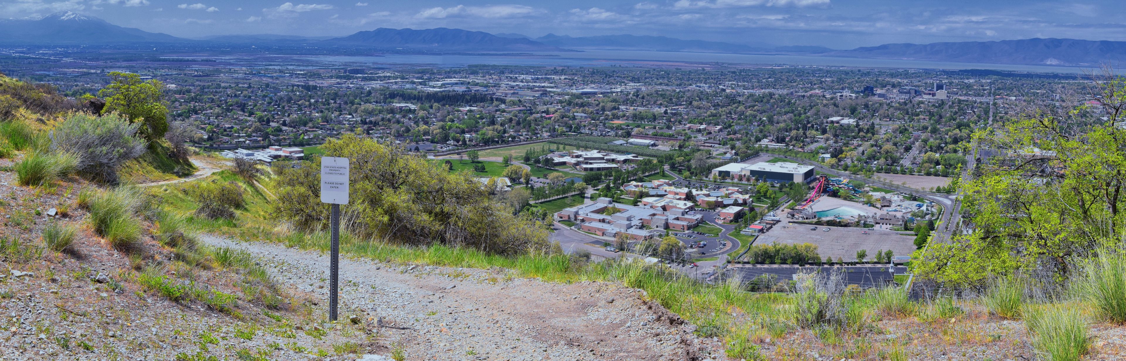 A mountainous landscape with a view of a town and a hospital sign indicating closure.