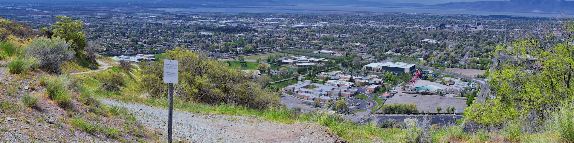 Paisagem montanhosa com vista para uma cidade e placa indicando que um hospital está fechado.