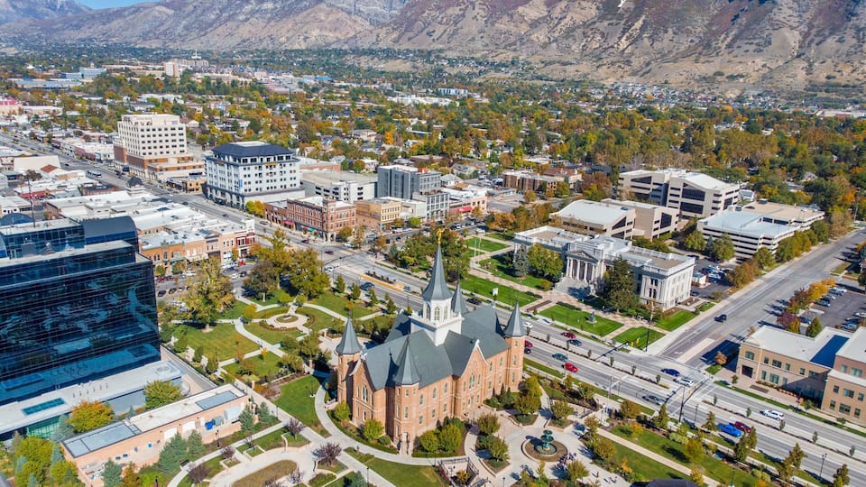 A cityscape with a prominent church, modern buildings, and a mountainous backdrop.
