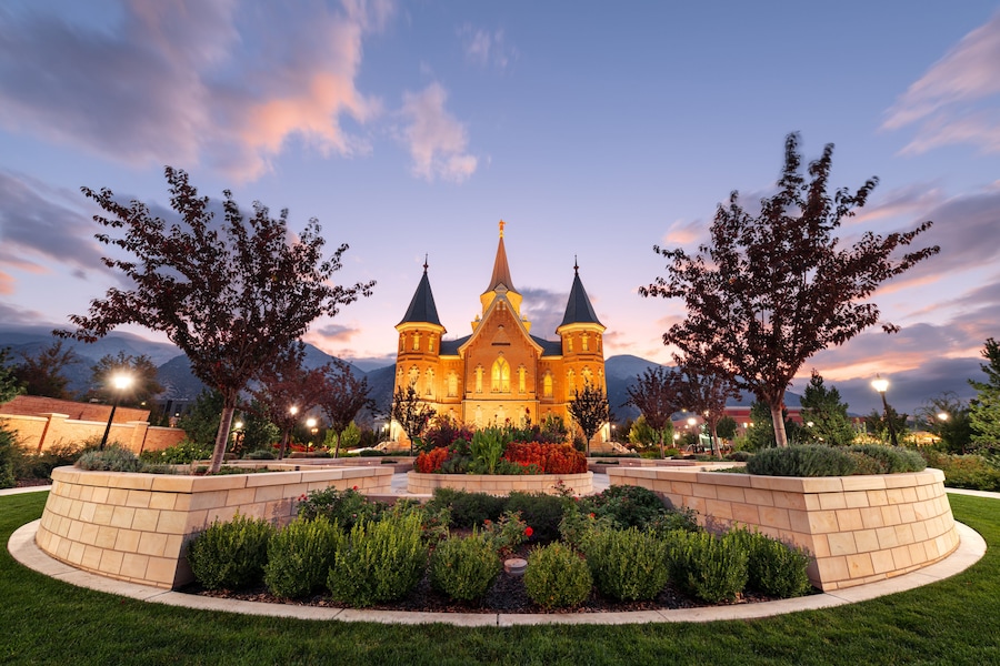 Una iglesia con dos torres, rodeada de jardines ajardinados y árboles.