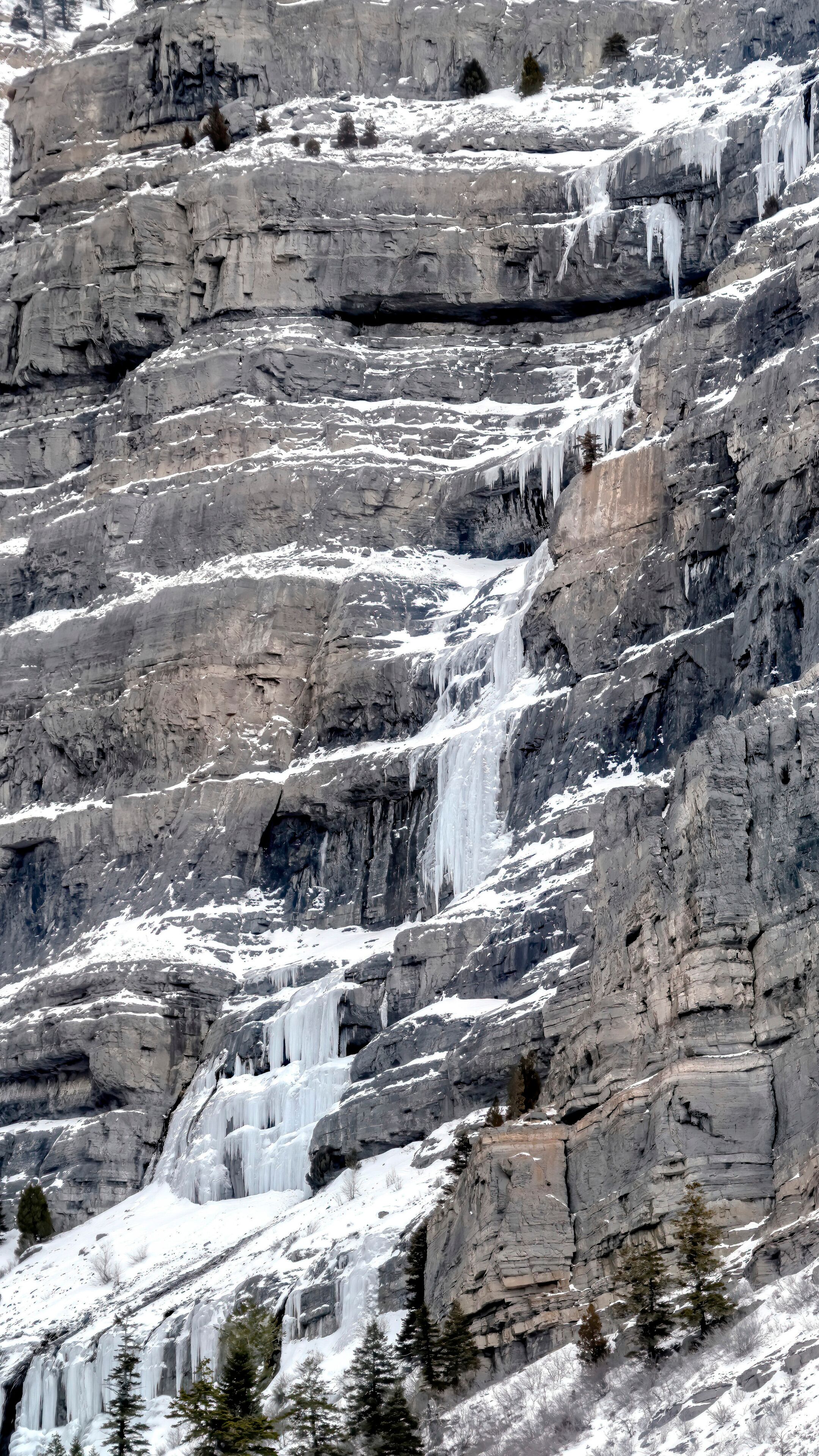 A snow-covered mountain with a waterfall cascading down its rocky slopes.