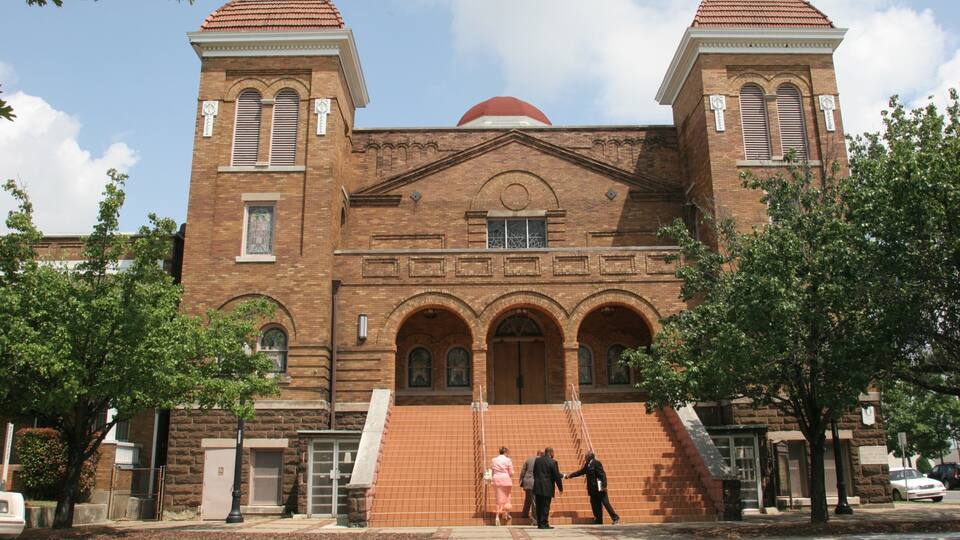 A large brick church with two towers and a red dome.
