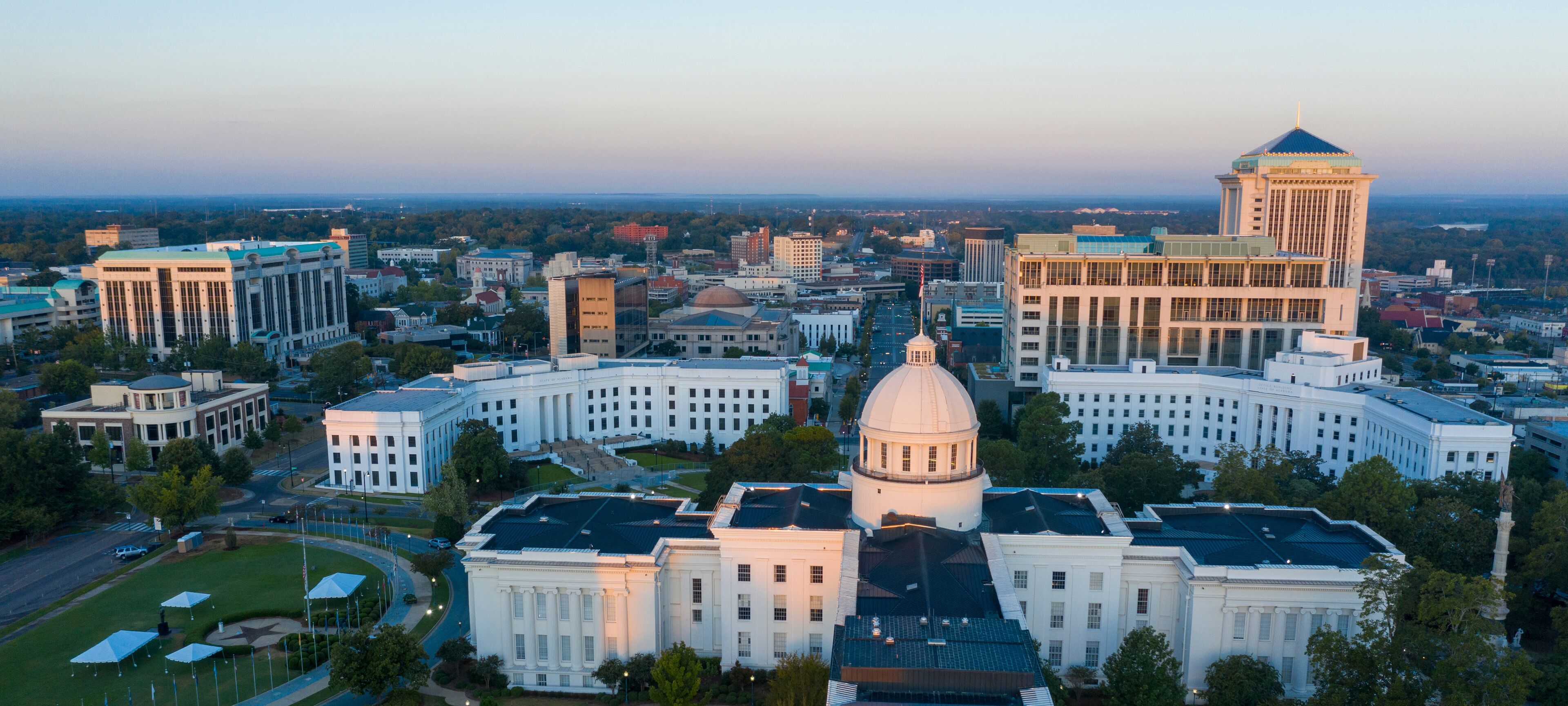 A cityscape with a prominent white building with a dome and a tall tower with a pointed roof.