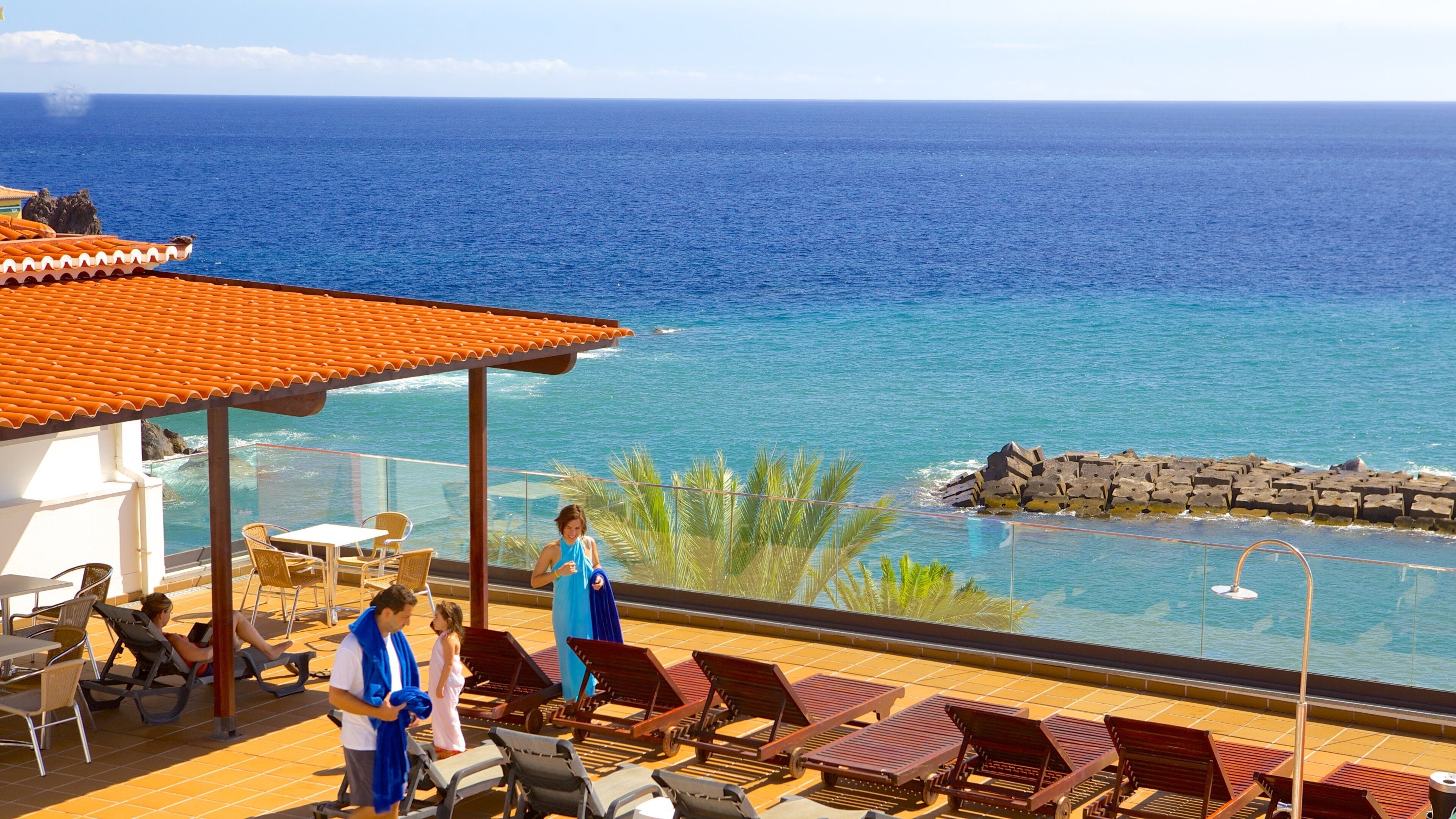 A coastal resort with a pool, lounge chairs, and a view of the ocean.