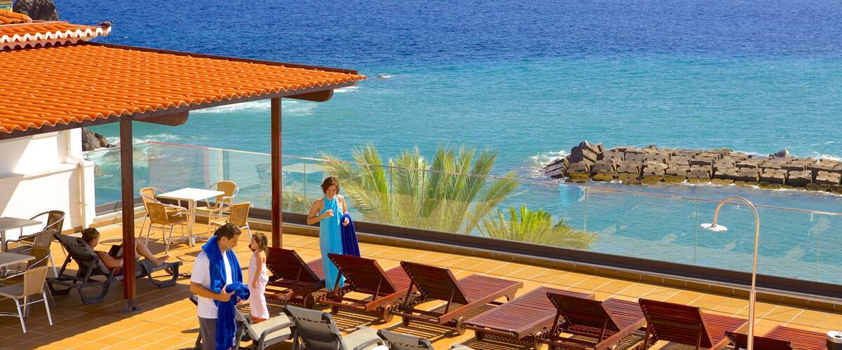 A coastal resort with a pool, lounge chairs, and a view of the ocean.