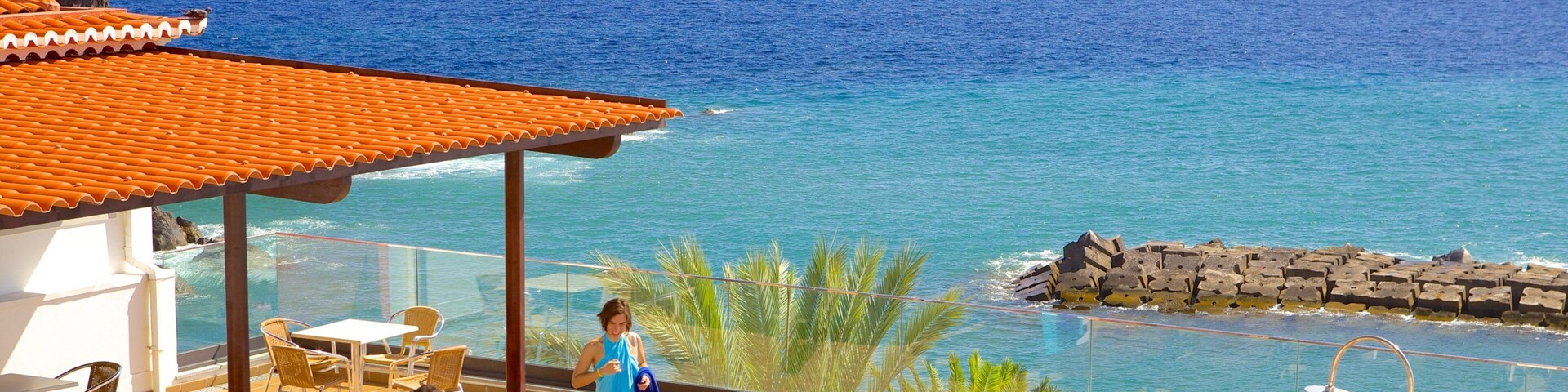 A coastal resort with a pool, lounge chairs, and a view of the ocean.