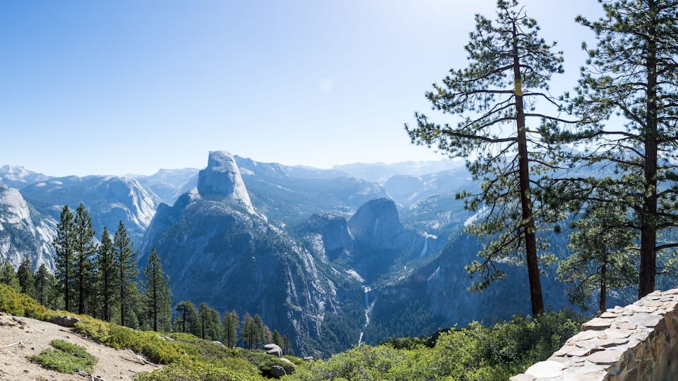A mountainous landscape with prominent rock formations and dense pine forests.