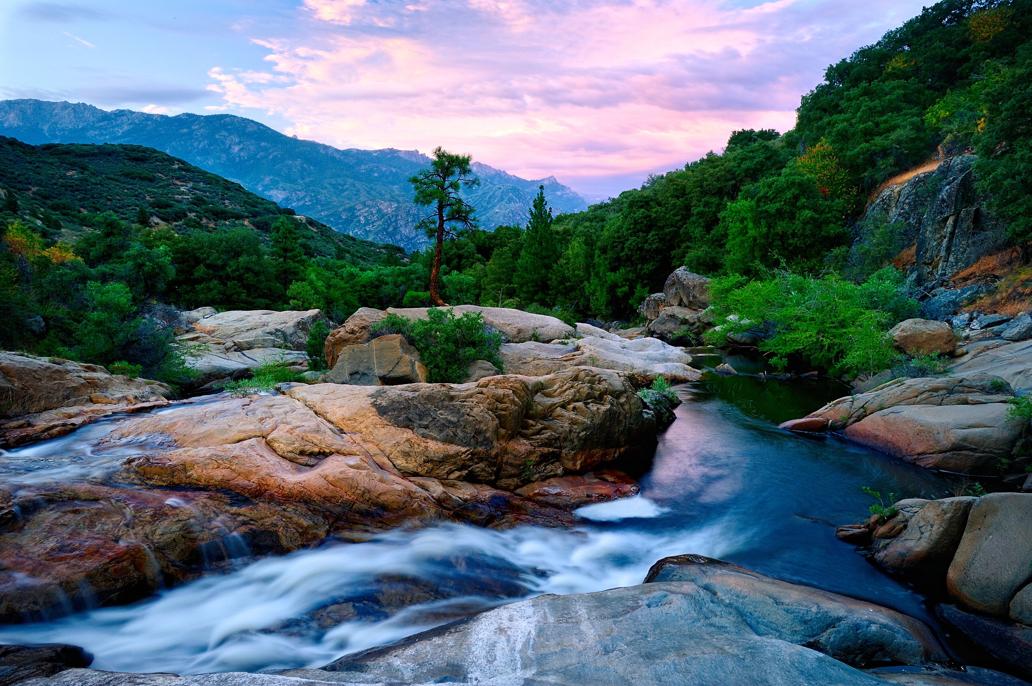 A river flowing through a rocky landscape with a mountain range in the background.