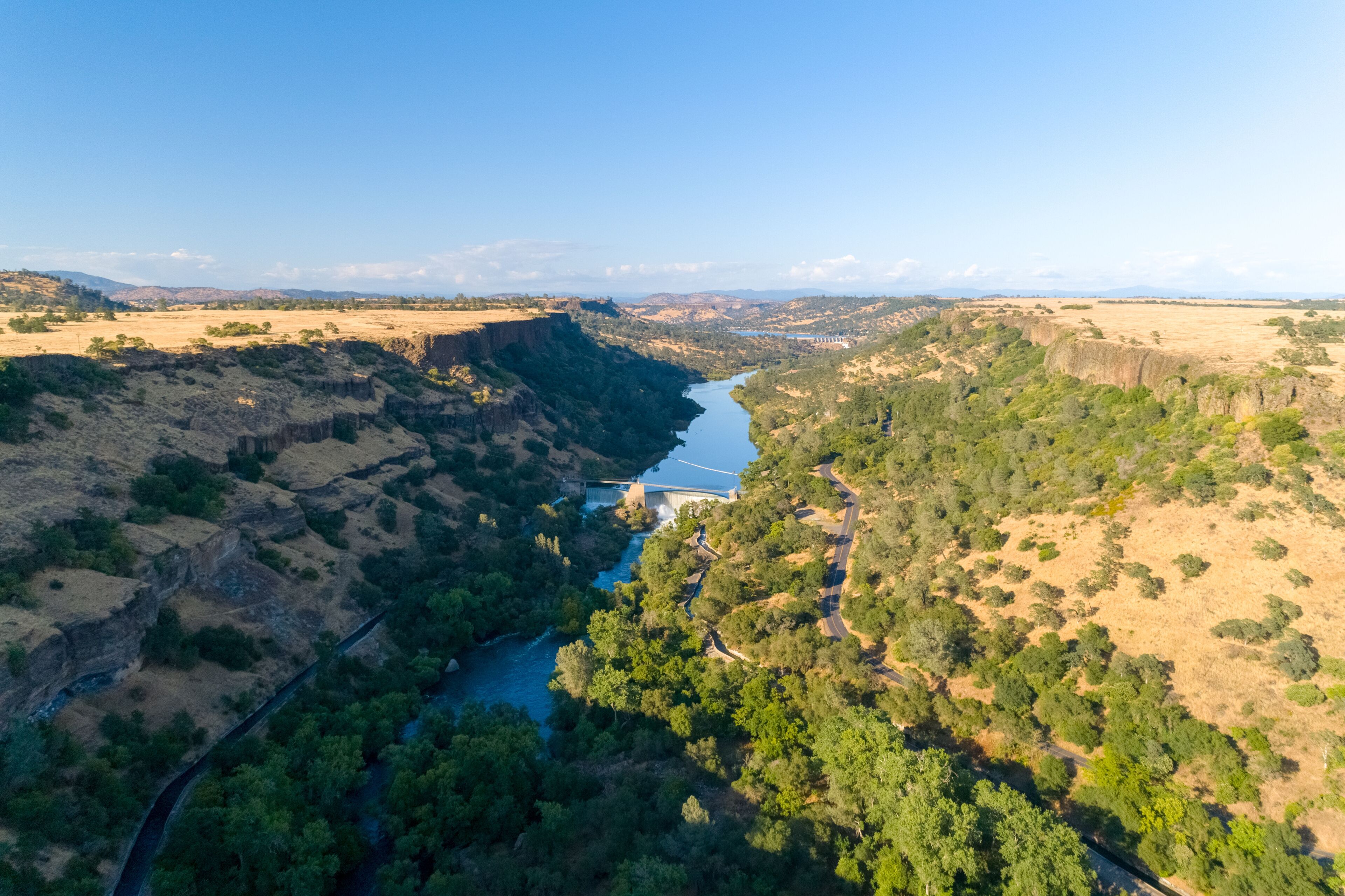 A river winding through a canyon with a bridge and a road.