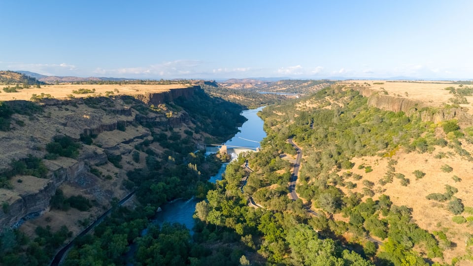 A river winding through a canyon with a bridge and a road.