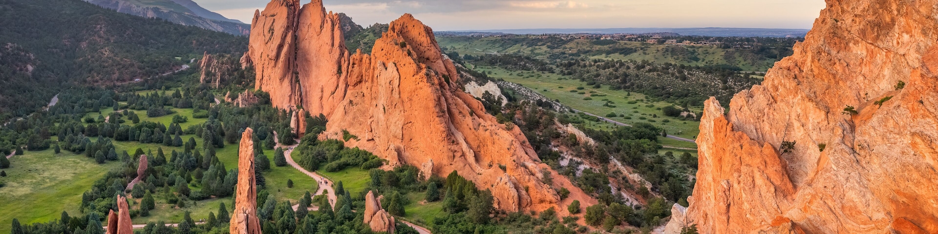 Paisagem montanhosa com formações rochosas avermelhadas e um caminho sinuoso.
