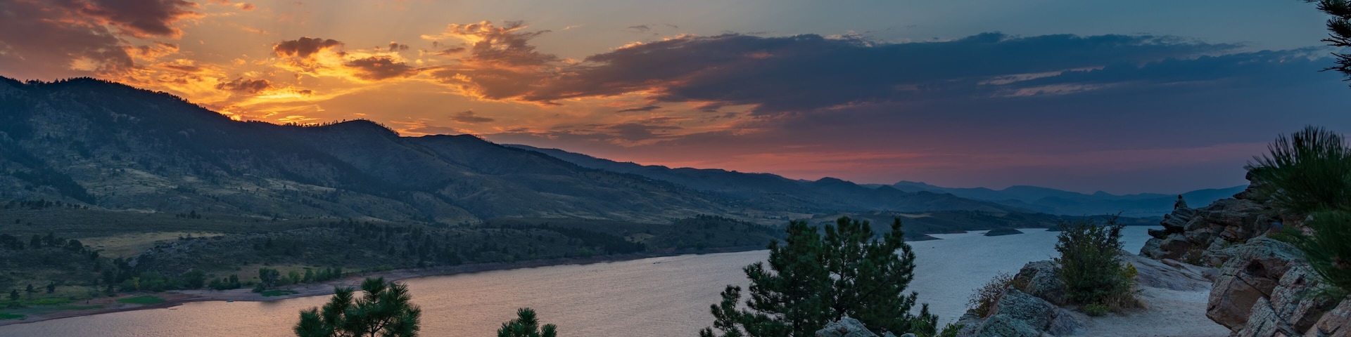 A mountainous landscape with a lake and a sunset.