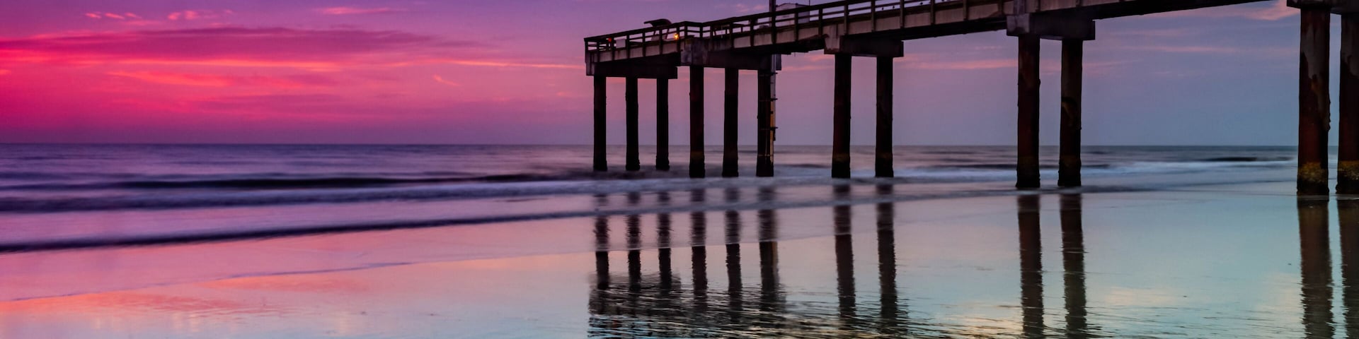 Un muelle se adentra en el océano bajo un cielo al atardecer.