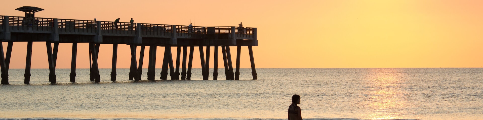 Ein Sonnenuntergang über dem Meer mit einem Steg, der sich ins Wasser erstreckt.