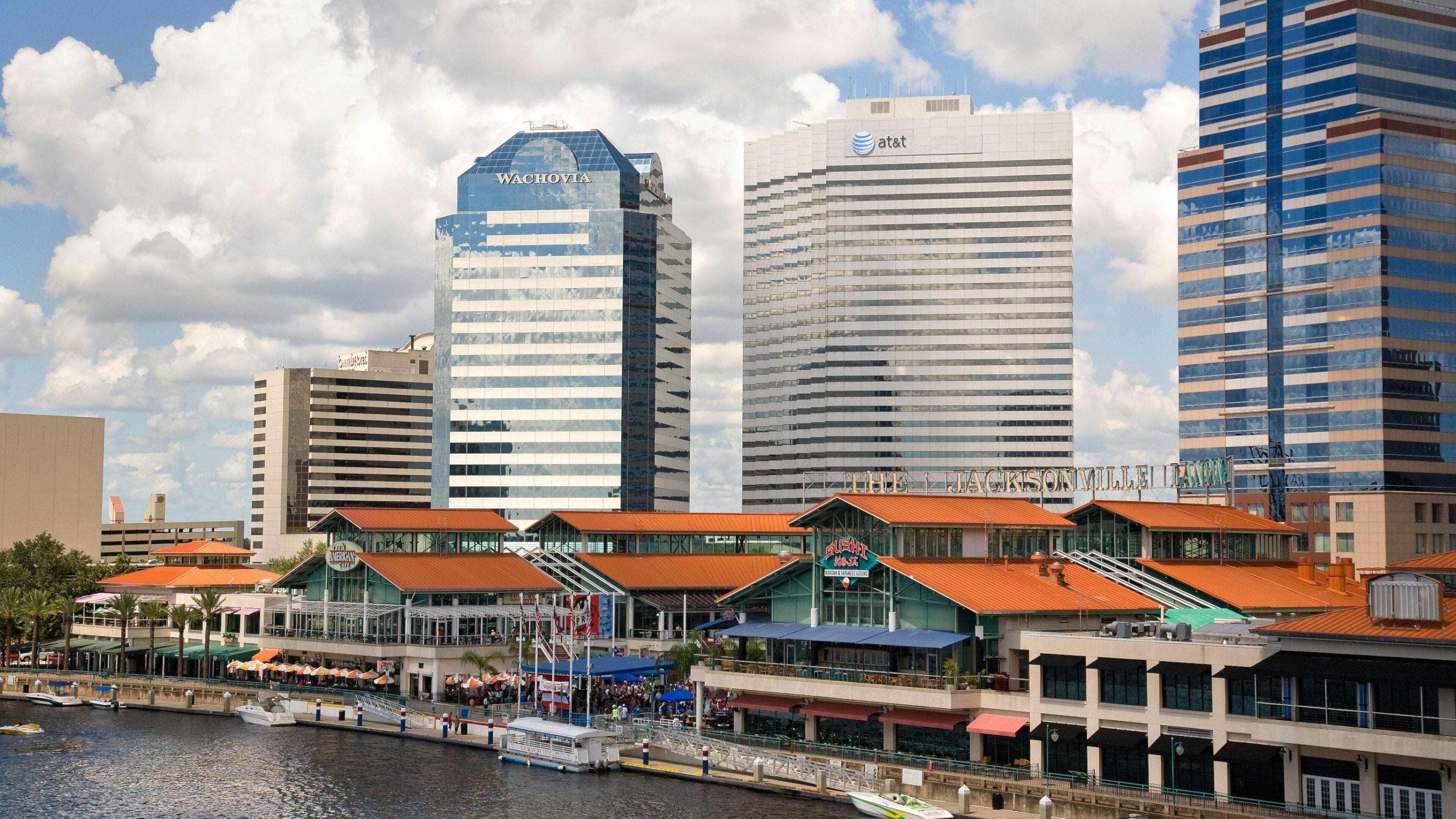A waterfront cityscape with modern buildings, including a prominent 'Wachovia' skyscraper, and a marina with boats.
