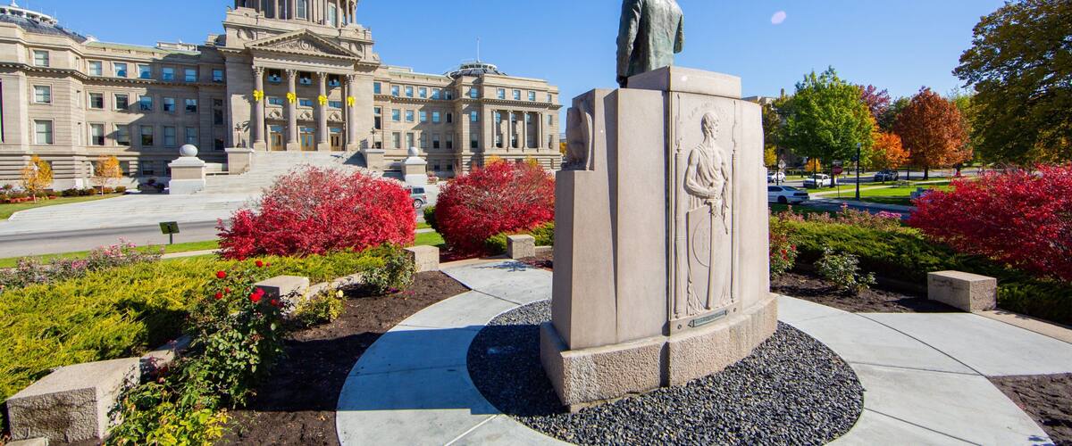 A statue in front of a large government building with a dome.