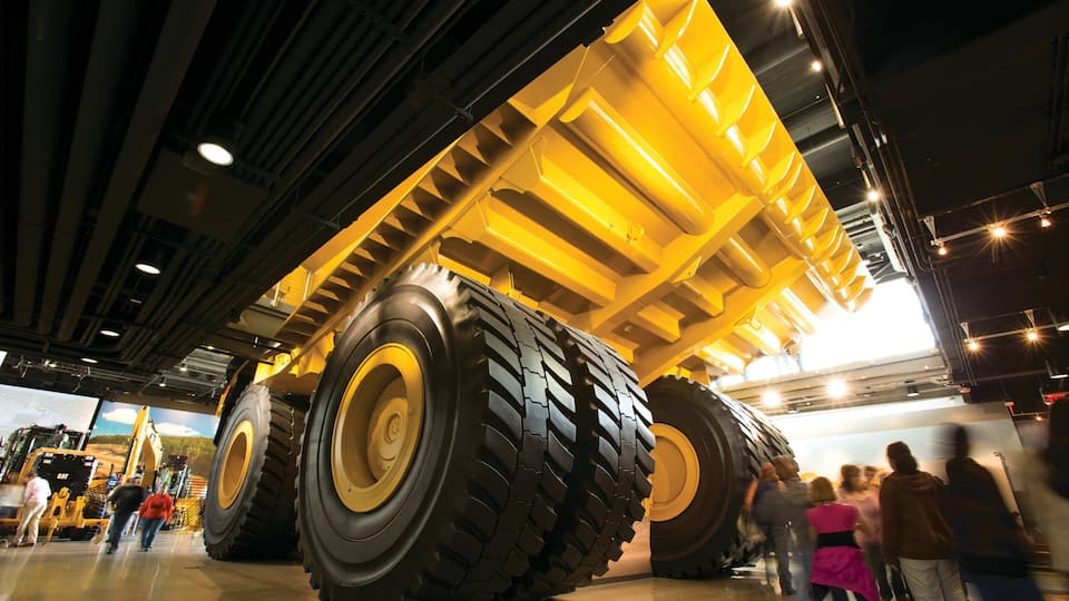 A large yellow construction vehicle with massive tires inside a building.