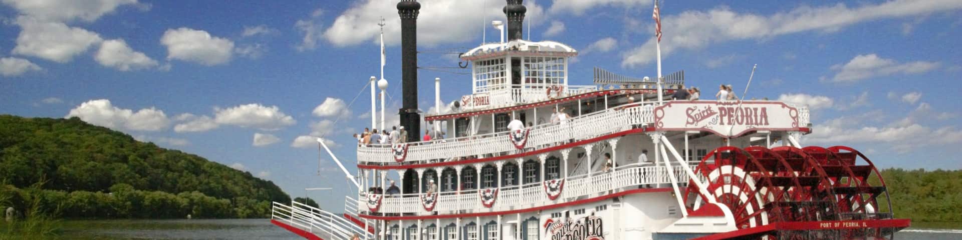 A steamboat named Spirit of Peoria traveling on a river.