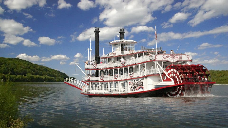 A steamboat named Spirit of Peoria traveling on a river.