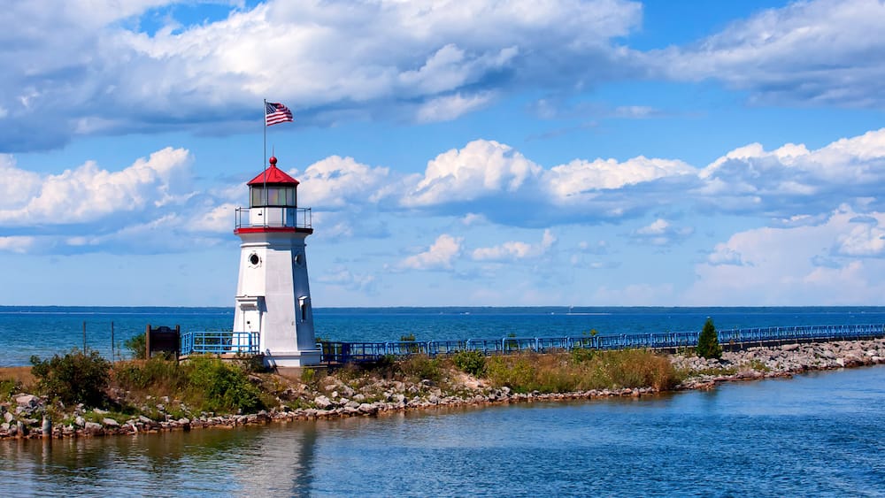 A lighthouse by a calm sea with a clear sky.