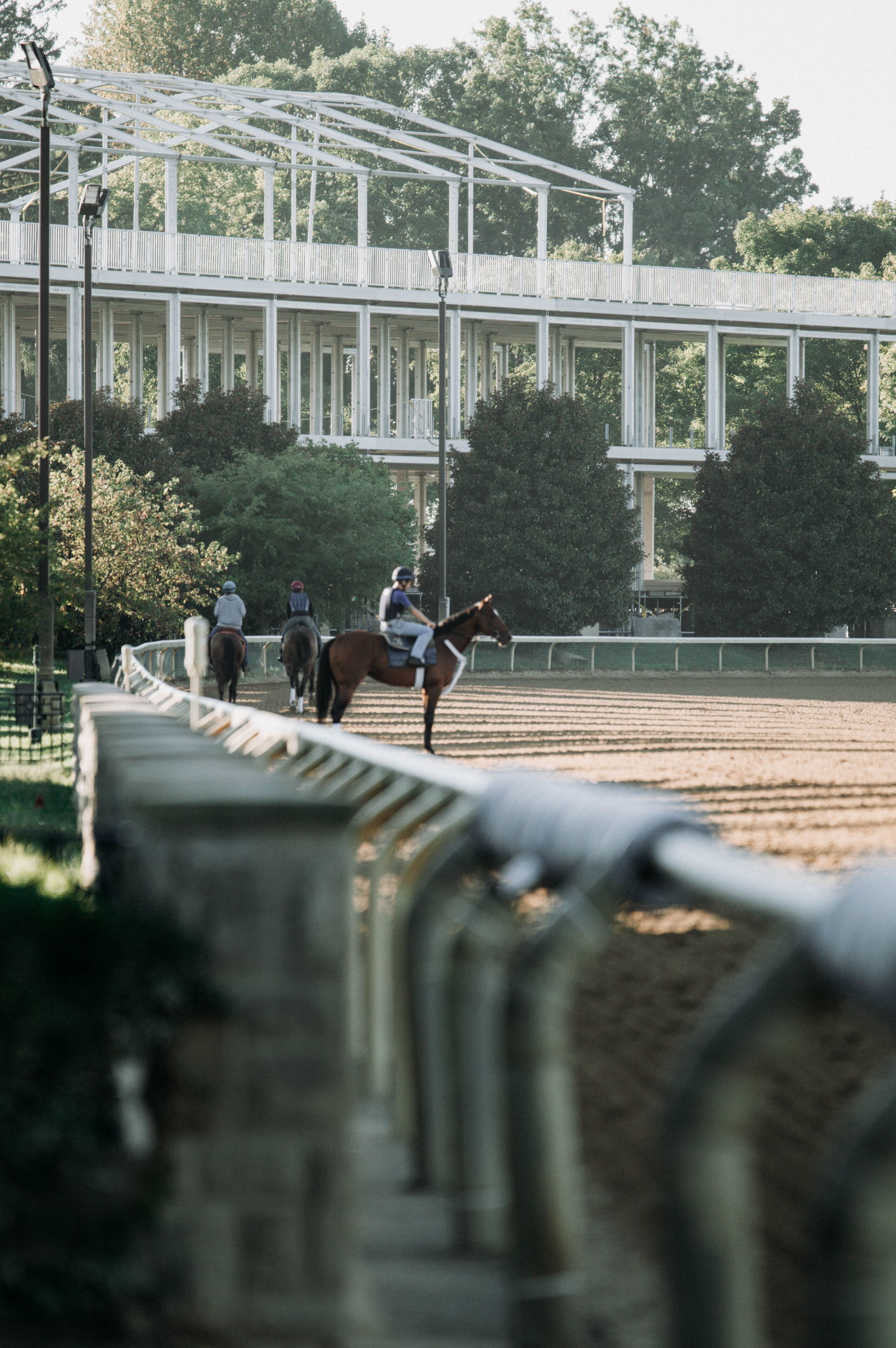 A horse race track with a white grandstand and trees in the background.