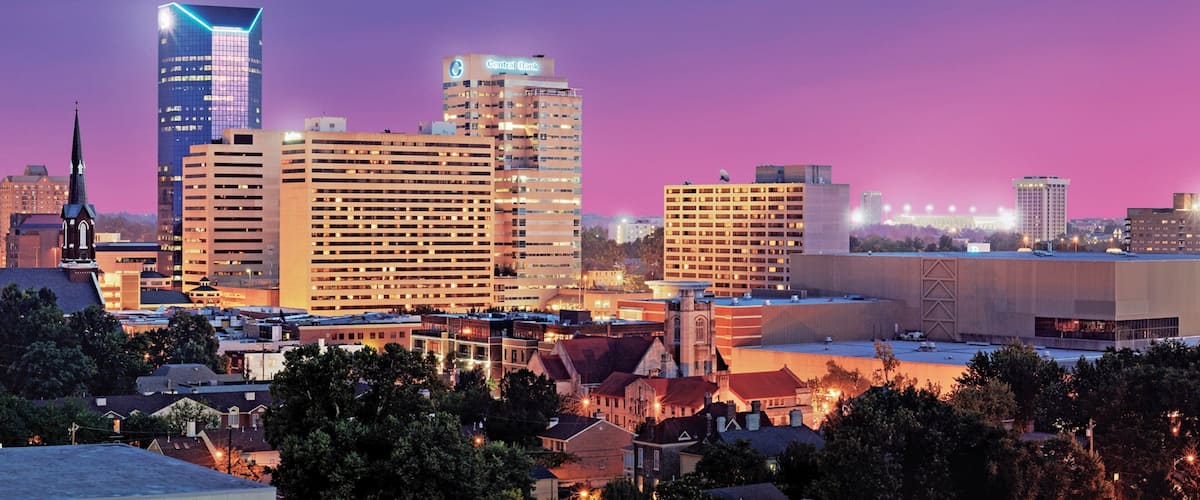 A city skyline with illuminated buildings and a church spire.
