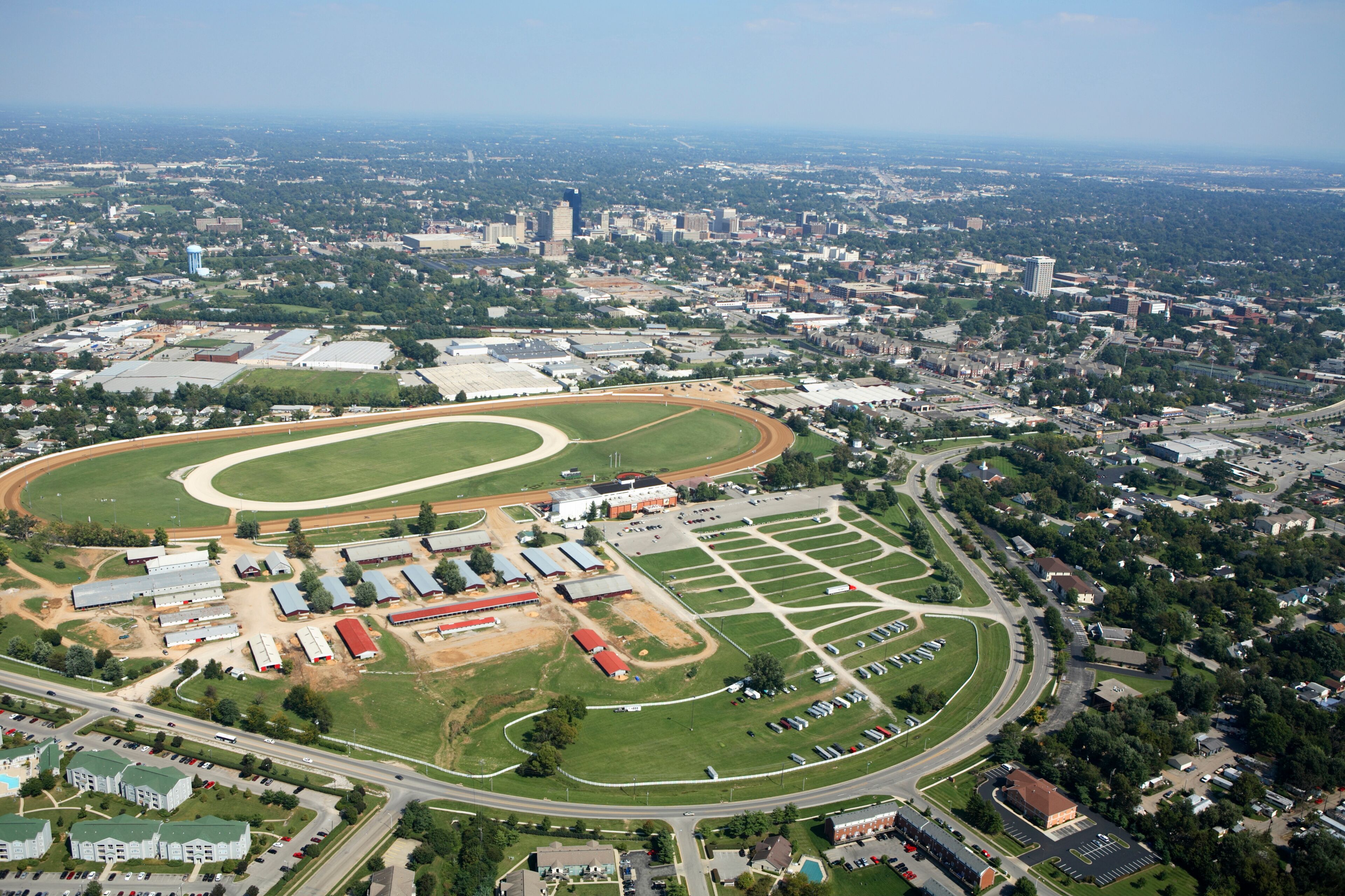 An aerial view of a large sports complex with a running track, stadium, and parking areas.