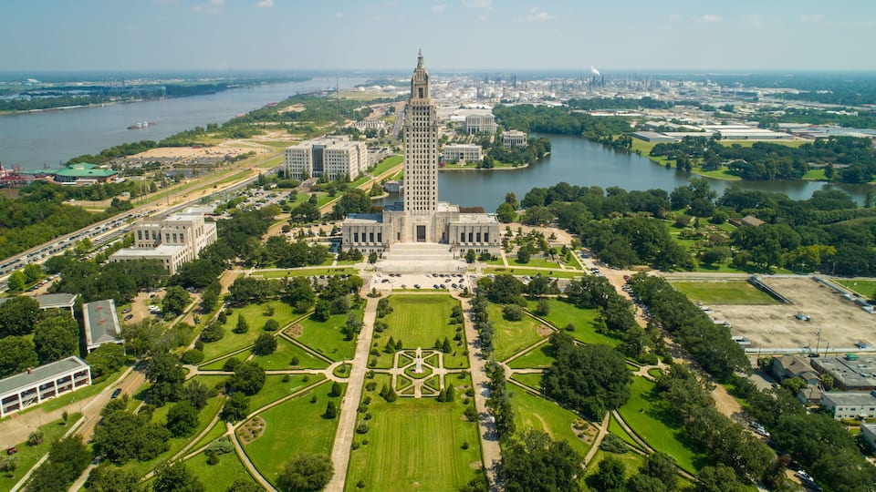 An aerial view of a city with a prominent tower, a river, and surrounding greenery.