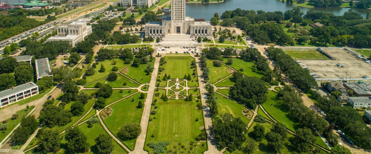 An aerial view of a city with a prominent tower, a river, and surrounding greenery.
