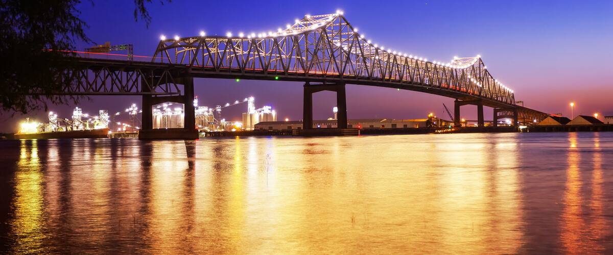 A bridge at dusk with lights reflecting on the water.