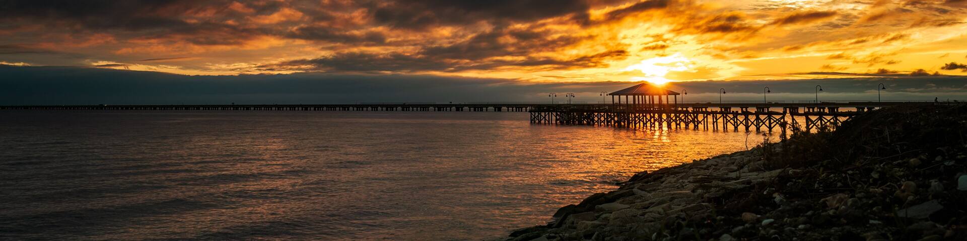 A sunset over a body of water with a pier extending into the distance.