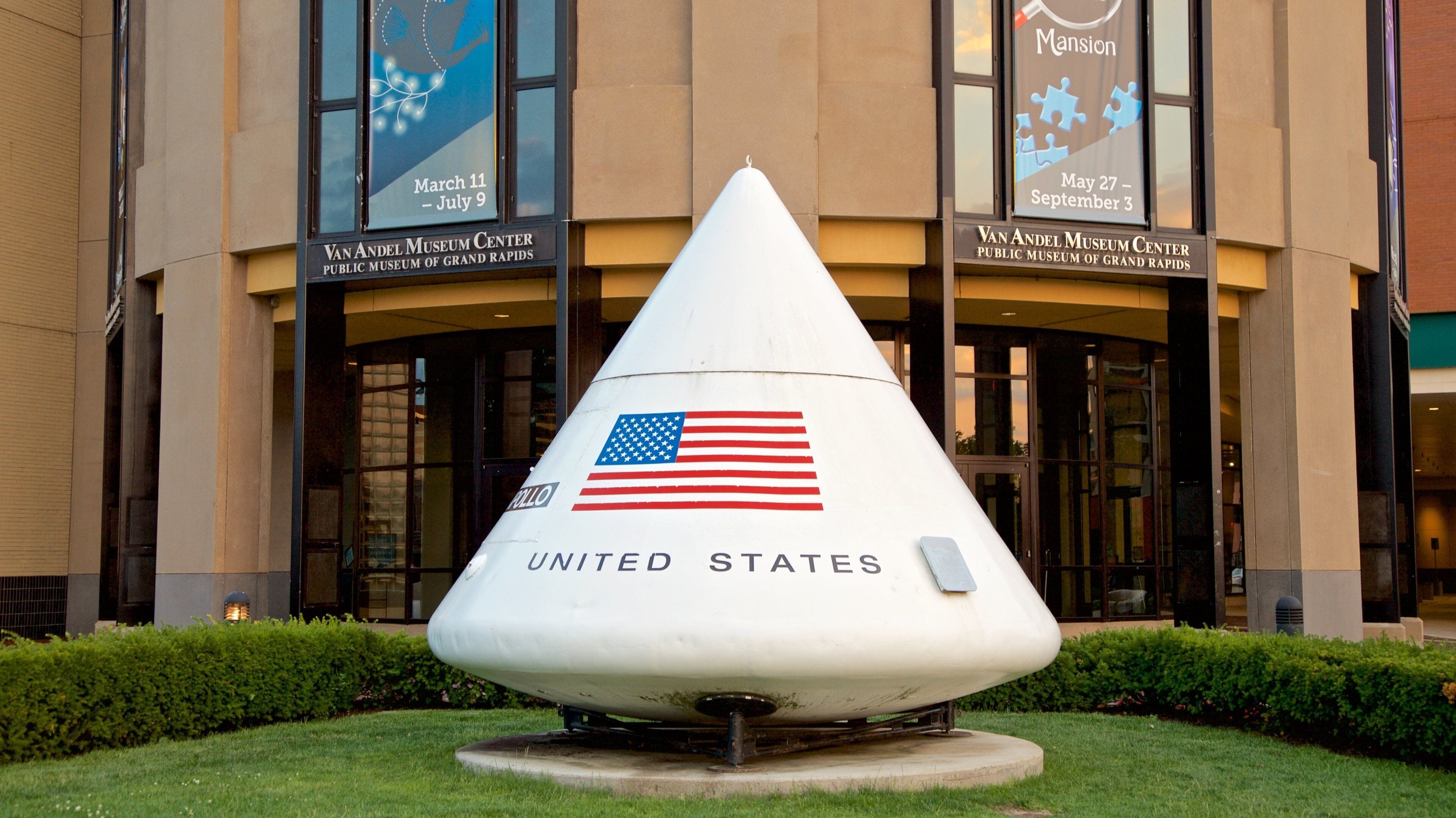 A space shuttle cone sculpture with an American flag, in front of the Van Andel Museum Center.