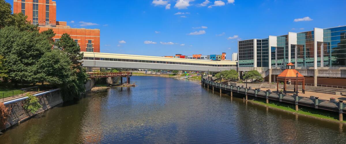 A river with a bridge, a red brick building, and modern glass buildings.