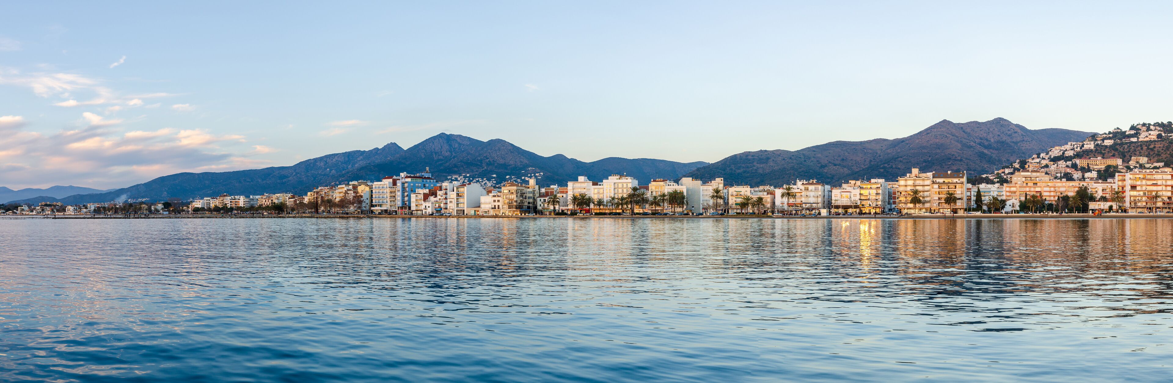 A coastal cityscape with a mountain range in the background.